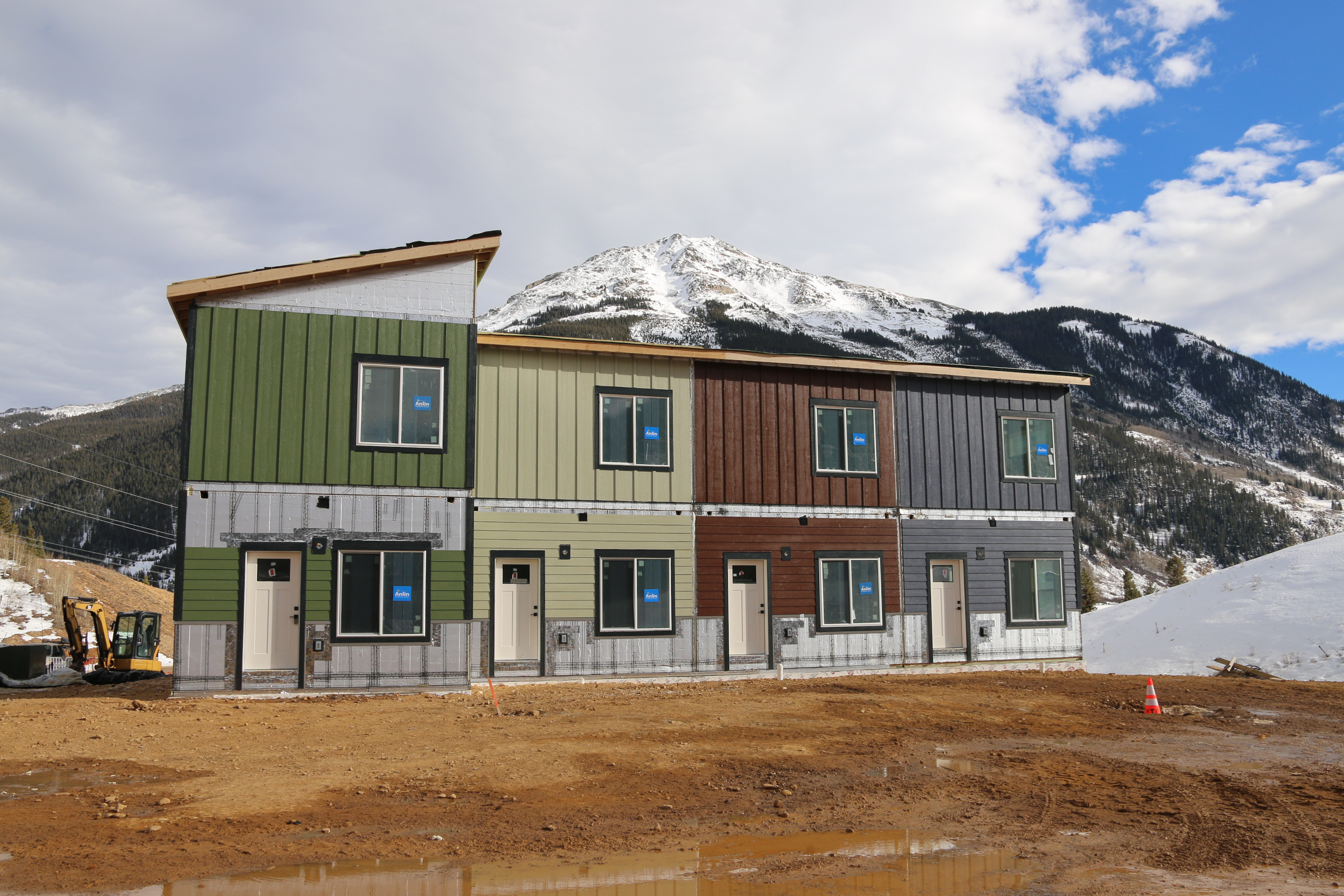 Photo of a four plex under construction with snow and mountains in background